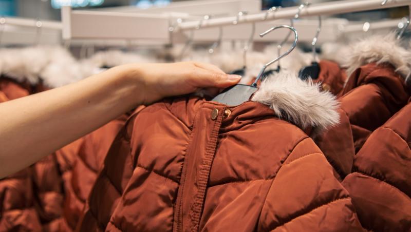 imagine cu mana unei femei care cumpara o geaca portocalie