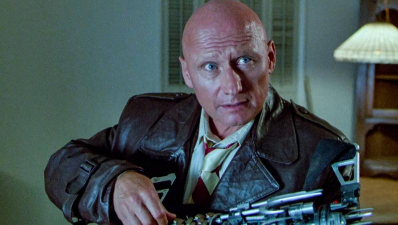 James Tolkan poartă o geacă neagră pe un fundal &icirc;nchis la culoare