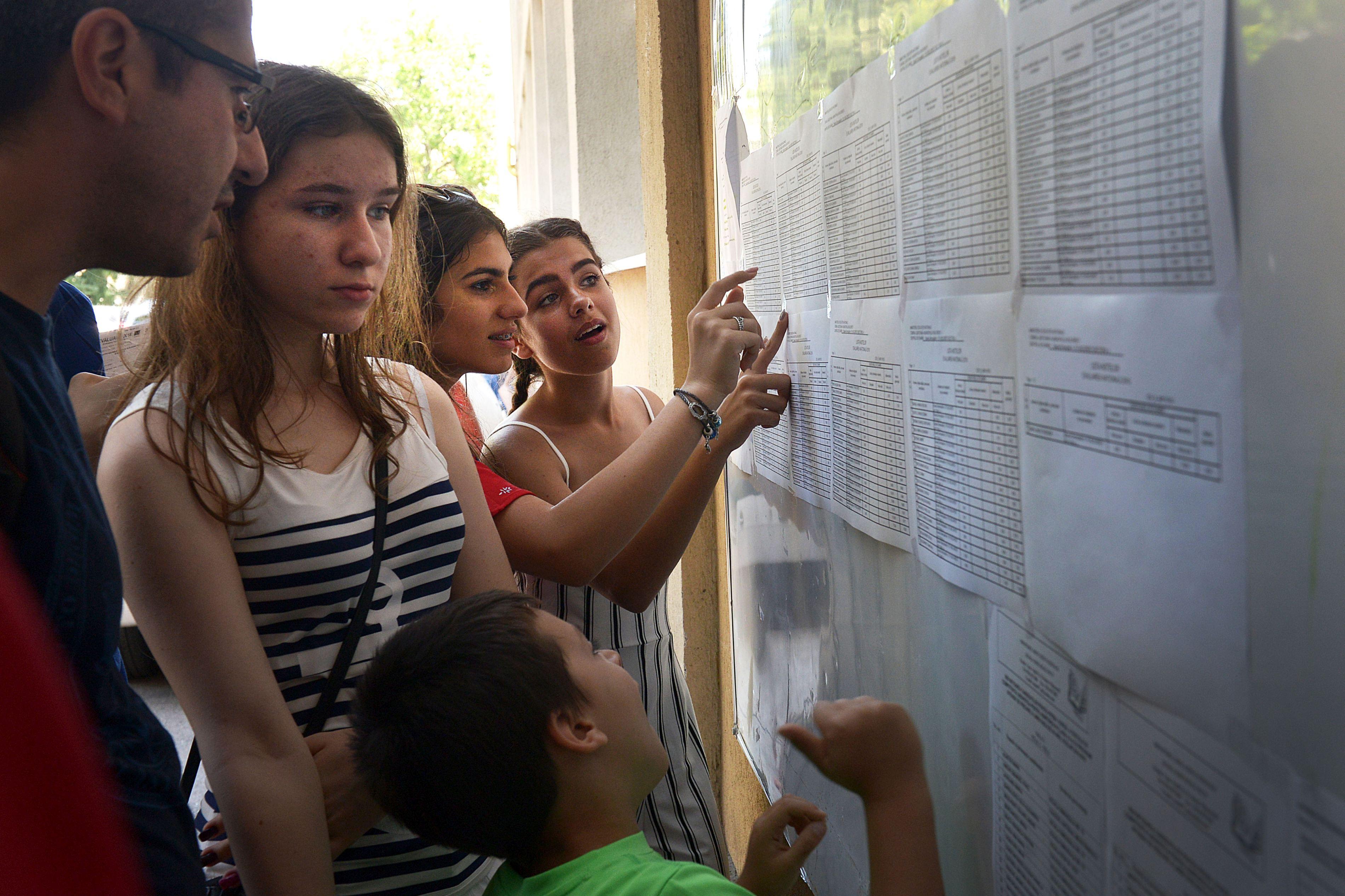 imagine cu elevi care isi cauta rezultatele la evaluarea nationala