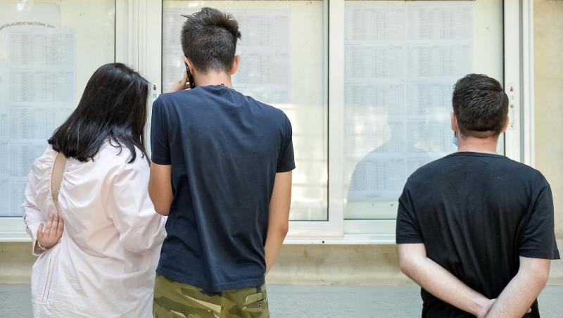 imagine cu elevi care isi cauta rezultatele la evaluarea nationala