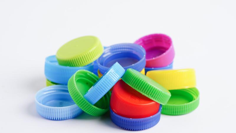 Capace colorate de sticle din plastic pentru reciclare, pe fundal alb.