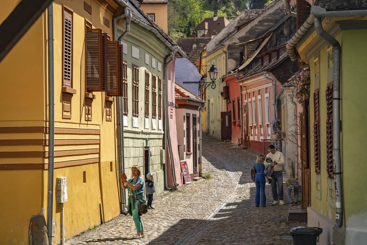 Turiști printre casele colorate din orașul vechi Sighișoara, Transilvania, România.