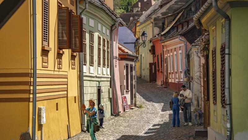 Turiști printre casele colorate din orașul vechi Sighișoara, Transilvania, Rom&acirc;nia.
