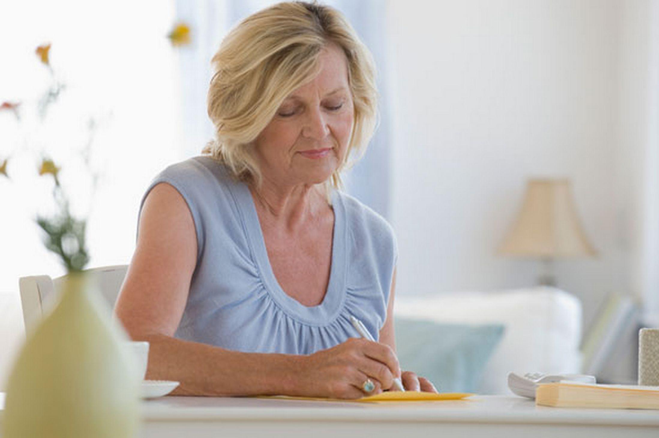 пожилая женщина пишет письмо. бизнес леди у окна с бумагами. женщина среднего возраста. взрослые женщины писали. девушка записывает в блокнот.