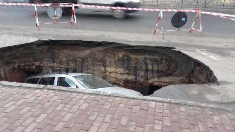 FOTO! ”Parcare” subterană peste noapte: Mașina unui șofer din Râmnicu Sărat a fost înghițită de un crater format în asfalt