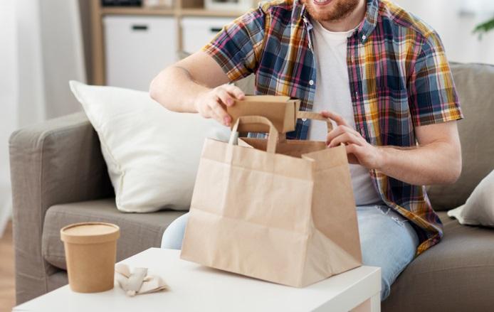 Un bărbat deschizând o pungă cu mâncare comandată