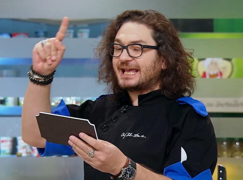 Florin Dumitrescu citind bonusul unei amulete, în ediția 38 din sezonul 9 „Chefi la cuțite”