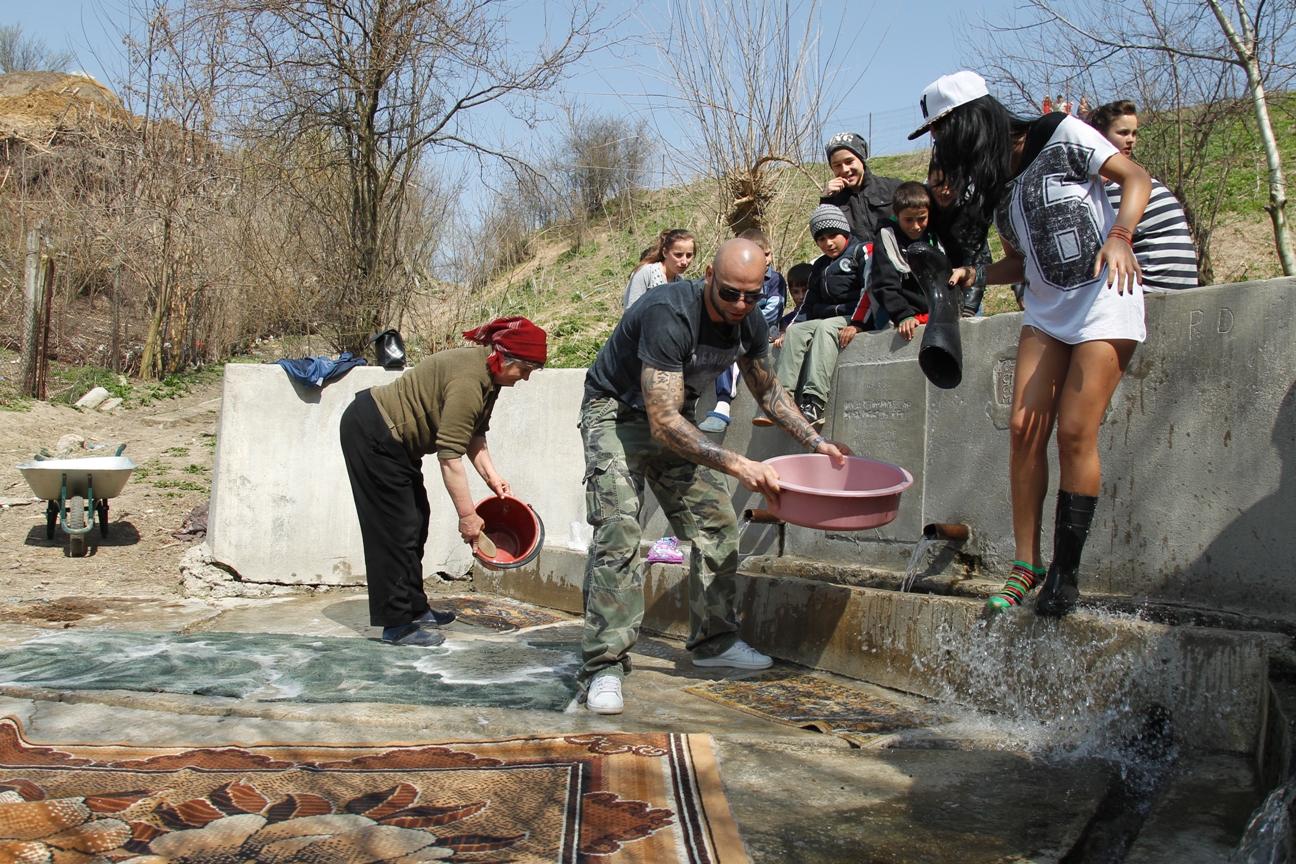 Margherita din Clejani și Giani Kiriță se bat cu apă în timp ce spală un covor