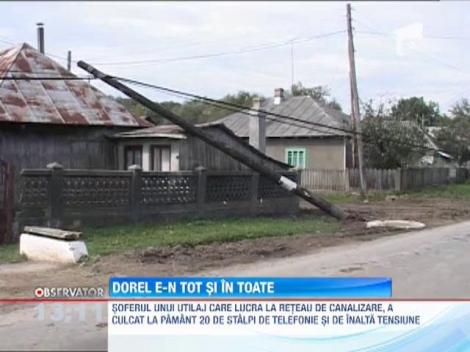 Soferul unui utilaj care lucra la reteaua de canalizare, a culcat la pamant 20 de stalpi de telefonie