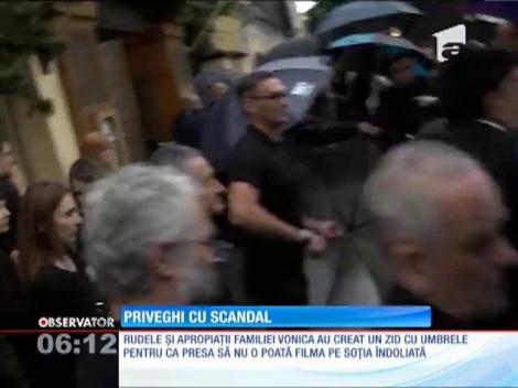 Soția milionarului Ilie Voica a venit la priveghi în spatele unui zid de umbrele