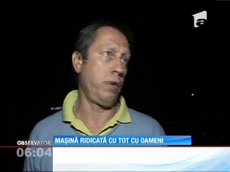 Trei oameni au fost ridicaţi pe o platformă, cu tot cu maşina pe care au lăsat-o în faţa unui magazin