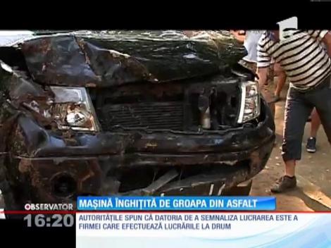 Maşină înghiţită de groapa din asfalt