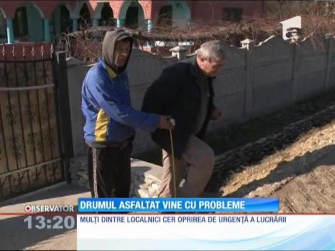 Drumul care urmează să fie asfaltat îi ține prizonieri în curți!