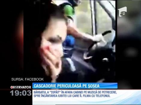 Cascadorie periculoasă. Dansează cu o mână pe volan, în afara camionului care rulează cu viteză pe şosea!