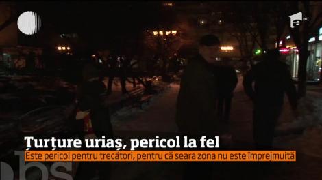 Un ţurţure uriaş atârnă de acoperişul unui bloc și se poate desprinde oricând