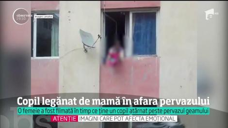 Imagini tulburătoare. O mamă din Zalău, filmată în timp ce îşi ţine copilul atârnat în afara pervazului de la geam