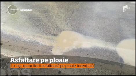 Mai mulţi muncitori au asfaltat o stradă din Iaşi pe o ploaie torenţială.