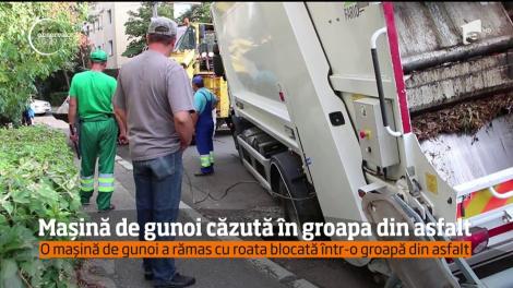 Imagini neobişnuite şi revoltătoare în Buzău. O maşină a firmei de salubrizare a rămas blocată cu roata într-o groapă din asfalt