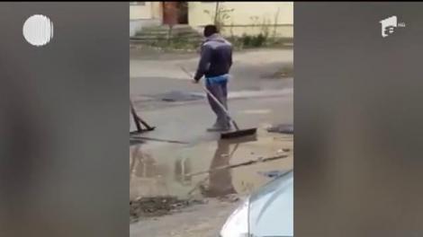 Marea asfaltare... din baltă. Un trecător i-a filmat pe muncitorii care se străduiau să acopere o groapă plină cu apă și noroi