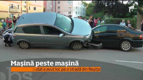 Scenă ca-n filme pe o stradă din Reşiţa. O maşină s-a urcat cu două din roţi pe un autoturism parcat