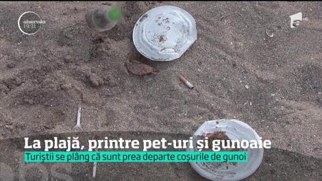 Turiștii stau la plajă, printre pet-uri și gunoaie