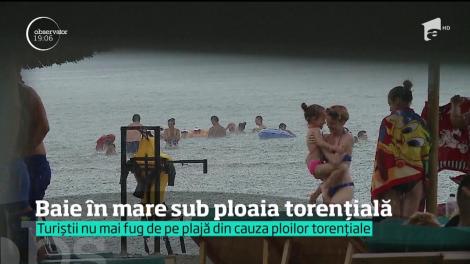 Baie în mare sub ploaia torențială