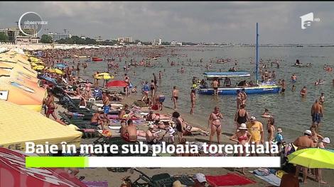 Baie în mare sub ploaia torențială