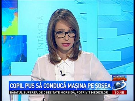 Copil pus să conducă maşina pe şosea