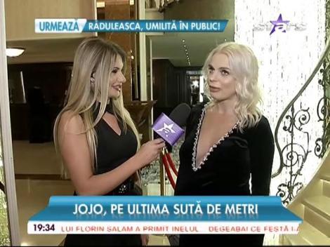 Mai are un pic şi naşte, dar Jojo poartă o rochie cu decolteu generos şi pantofi cu toc: "Cred că Achim şi-a chemat cumva surioara"